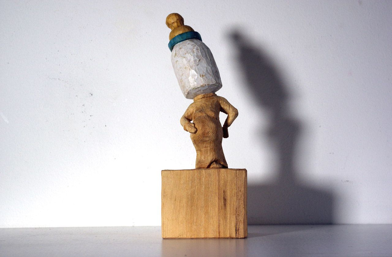 Holzskulptur aus der Reihe Neard Heads (mit Babymilchflasche ) von Nadine Elda Rosani